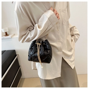 Detail of black quilted bucket bag with gold chain strap and pearl drawstring accents