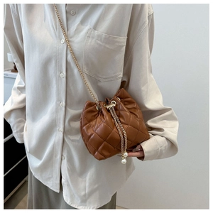 Detail of a brown quilted bucket bag with golden chain strap and elegant pearl accents