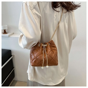 Brown quilted bucket bag with gold chain strap and pearl drawstring details shown on model