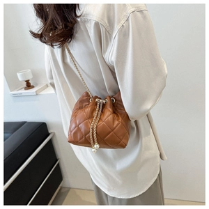 Detail of brown quilted bucket bag with gold chain strap and pearl drawstring accents