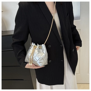 Silver quilted bucket bag with gold chain strap and pearl drawstring detail on model