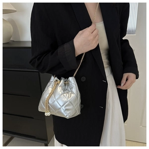 Silver quilted bucket bag with gold chain and pearl drawstring shown on a model