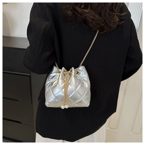 Detail of silver quilted bucket bag with pearl drawstring and thin metal chain strap