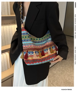 Detailed shot of ethnic style woven shoulder bag with colorful tassels and patterned strap