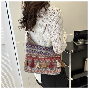 Detail view of ethnic style woven shoulder bag with geometric patterns and long tassels