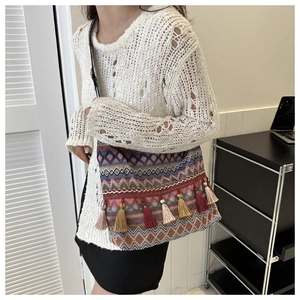 Detailed close-up of Bohemian woven shoulder bag with colorful ethnic patterns and tassels