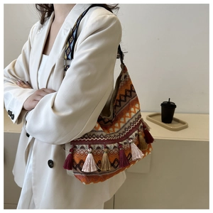 Detail of bohemian tote bag with geometric patterns, colorful tassels and woven strap