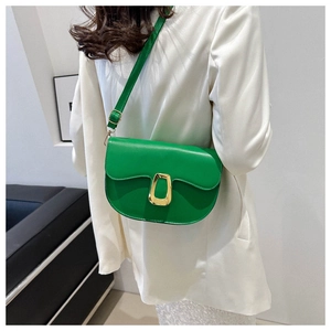 Detail of bright green saddle bag with gold buckle worn on a white blazer