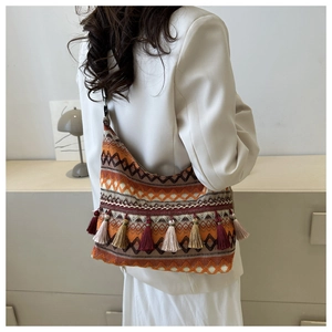 Bohemian style woven tote bag with colorful fringe tassels shown on a model's shoulder