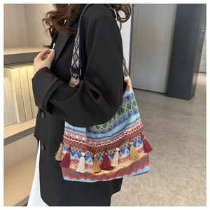 Detail of bohemian knit shoulder bag with colorful geometric patterns and long fringe