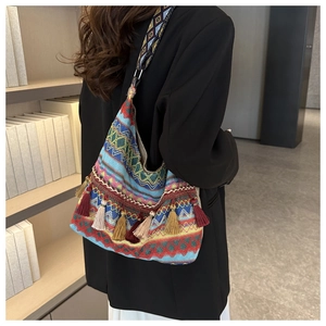 Detail of colorful woven bohemian crossbody bag with long fringes and geometric strap