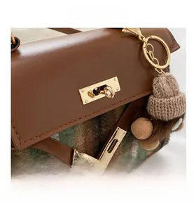 Detail shot of brown plaid handbag showing golden twist-lock closure and fabric texture