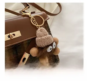 Close-up of a brown fluffy monster charm with a knit hat on a vintage checkered bag