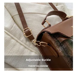 Detailed close-up of the adjustable buckle and golden hardware on the brown leather bag