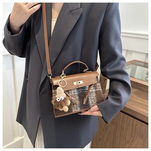 Detail of plaid leather handbag with metallic twist lock and cute monster charm