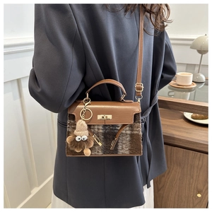 Detail of vintage plaid handbag with brown leather flap and funny plush pendant accessory