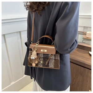 Detail of checkered shoulder bag with gold twist lock and plush charm accessory
