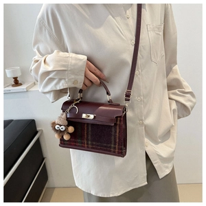 Detail of vintage plaid handbag with burgundy leather and golden twist lock closure