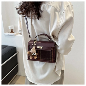 Detail of vintage burgundy plaid handbag featuring a plush bear charm and gold hardware