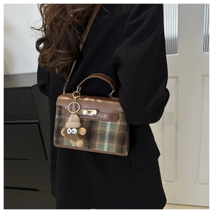 Detail of retro plaid handbag with brown leather, gold twist lock and a cute monkey charm