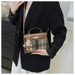 Detail of checkered tweed crossbody bag with brown leather trim and cute plush charm