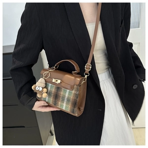 Detail of checkered shoulder bag featuring a gold clasp and cute plush doll pendant