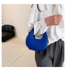 Detail of royal blue crescent underarm bag with crocodile texture and gold hardware
