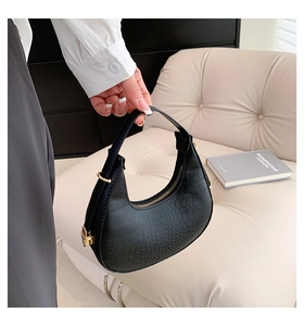 Detail of black hobo bag with crocodile embossed texture and elegant gold hardware