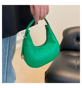 Close-up of vibrant green crescent hobo bag featuring glossy crocodile embossed texture