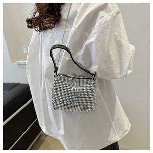 Detailed view of silver rhinestone handbag with metallic chain strap and black handle