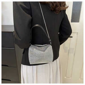 Detail of silver rhinestone mini bag with black leather handle and metallic chain strap