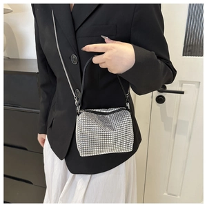 Detail view of silver rhinestone handbag with black handle and sparkling crystal surface