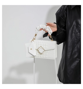 Detail of white crocodile embossed mini square bag with cloud-shaped pleated handle and lock