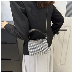 Close-up of silver rhinestone mini bag with metallic chain and black leather handle