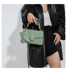 Detail view of sage green quilted handbag with crocodile texture and pleated handle