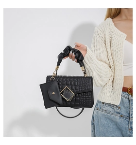 Detail of black stone-patterned crossbody bag with metal buckle and ruffled handle