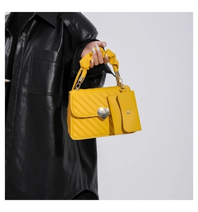 Close-up of yellow quilted handbag with heart buckle and matching mini pouch attachment