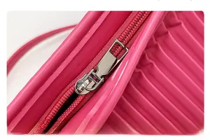 Detail view of silver metal zipper and pleated leather texture on fuchsia crossbody bag
