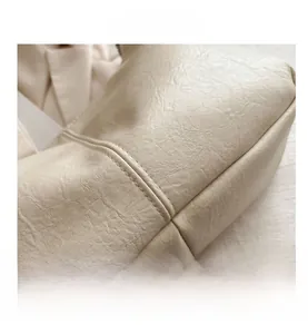 Macro shot of beige leather texture and fine stitching on a minimalist tote bag corner