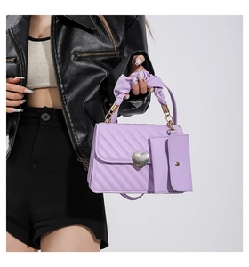 Detail of light purple quilted handbag with heart clasp and ruched handle