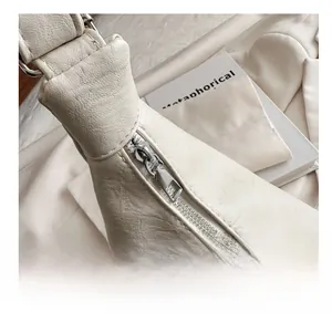 Detail of silver smooth zipper and pebble leather texture on off-white shoulder bag