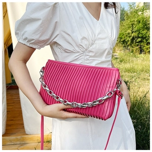 Detail of rose red pleated handbag with silver chain and leather strap on model