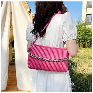 Detail of rose pink pleated shoulder bag with silver chain in outdoor setting