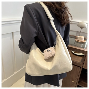 Detail of off-white tote bag featuring lychee texture and a khaki plush bear charm