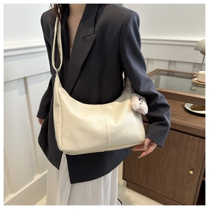 Close-up of beige half-moon tote bag with pleat texture and cute plush charm