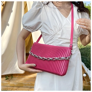 Close-up of fuchsia pleated crossbody bag with bold silver metal chain and thin strap