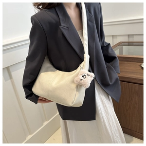 Detail of cream white crescent shoulder bag with plush bear charm and faux leather texture