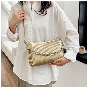 Close-up of champagne gold pleated crossbody bag with bold silver chain and leather strap