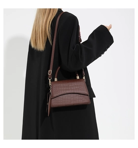 Detail of dark brown crocodile-textured bag with golden hardware and woven handle
