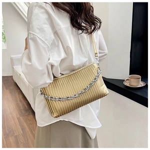 Detail of gold pleated texture shoulder bag with stylish chunky silver chain decoration